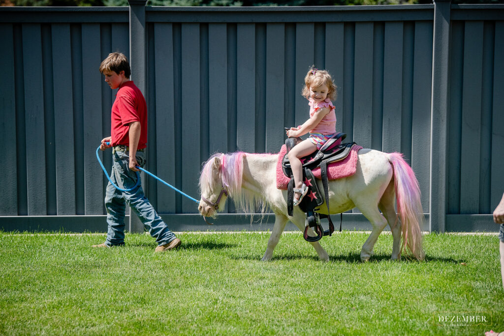 Little girl rides petting zoo pony