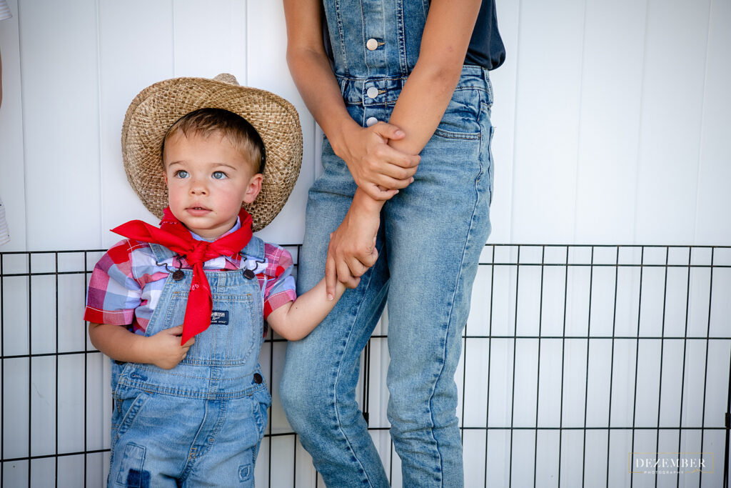 Little boy dressed as farmer holds sister's hand