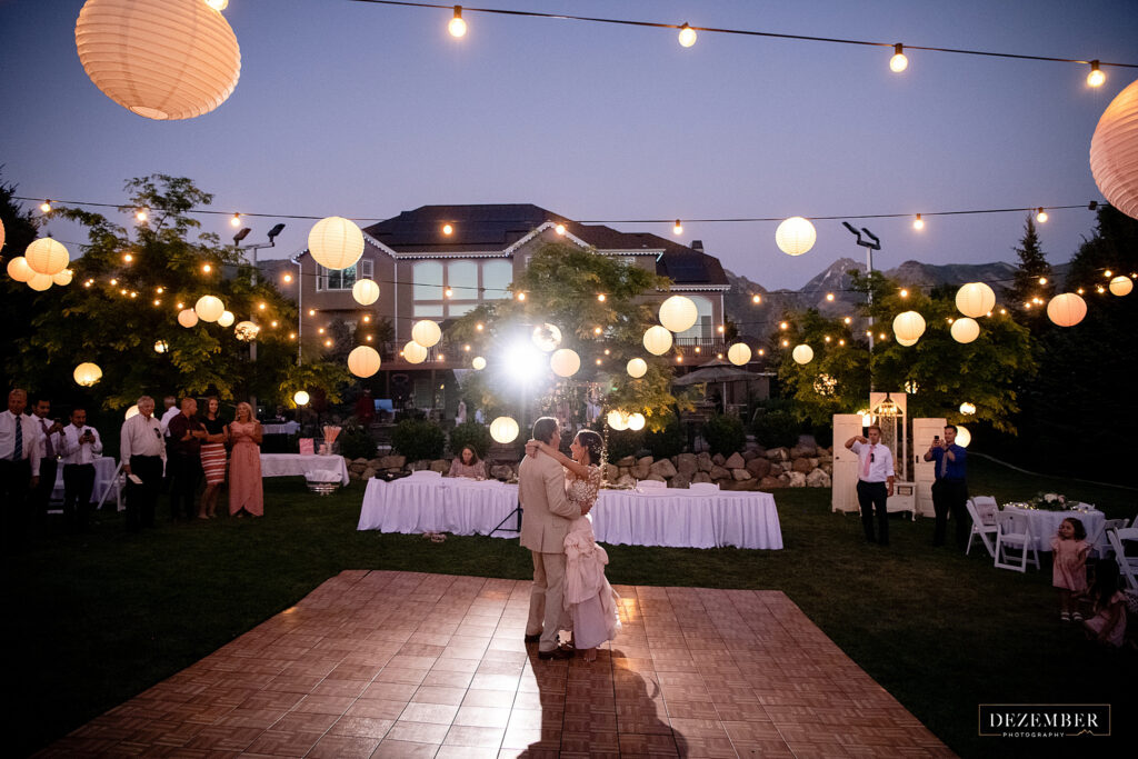 Elegant backyard wedding reception first dance under the string lantern lights