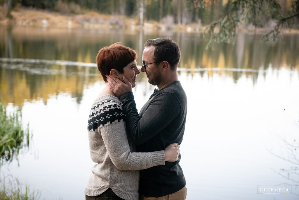 Couple holds each other in front of lake