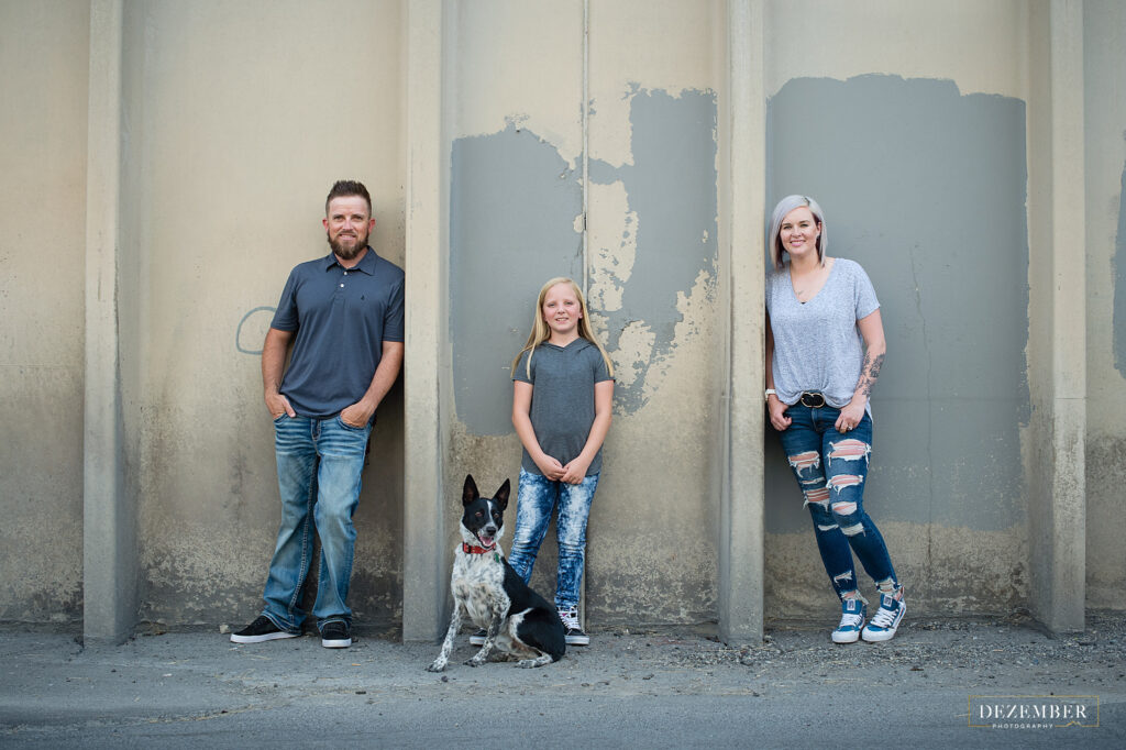 Family posing with their pup on an urban wall