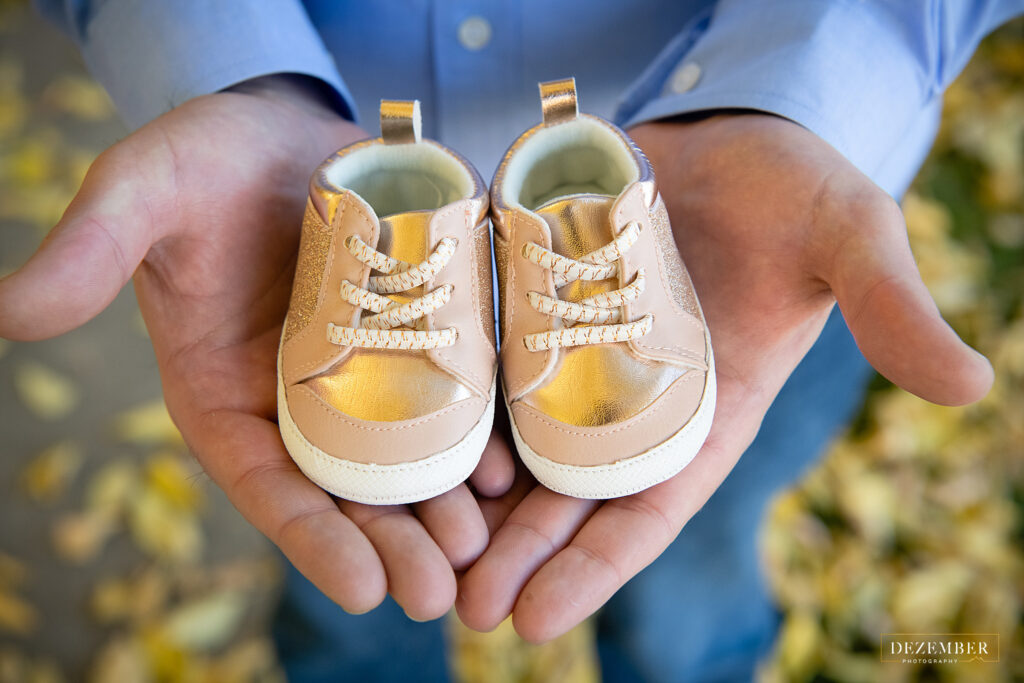 Man holds baby shoes in the palms of his hands