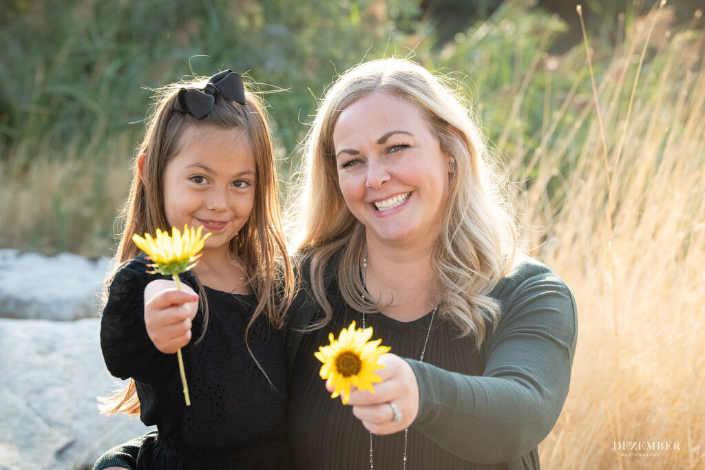 Mom and daughter hold out yellow flowers