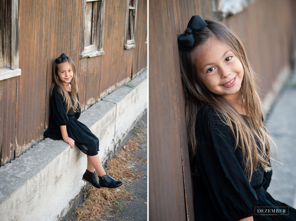 Little girl in black dress smiles for portraits