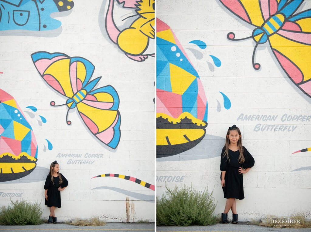 Girl poses in front of butterfly graffiti