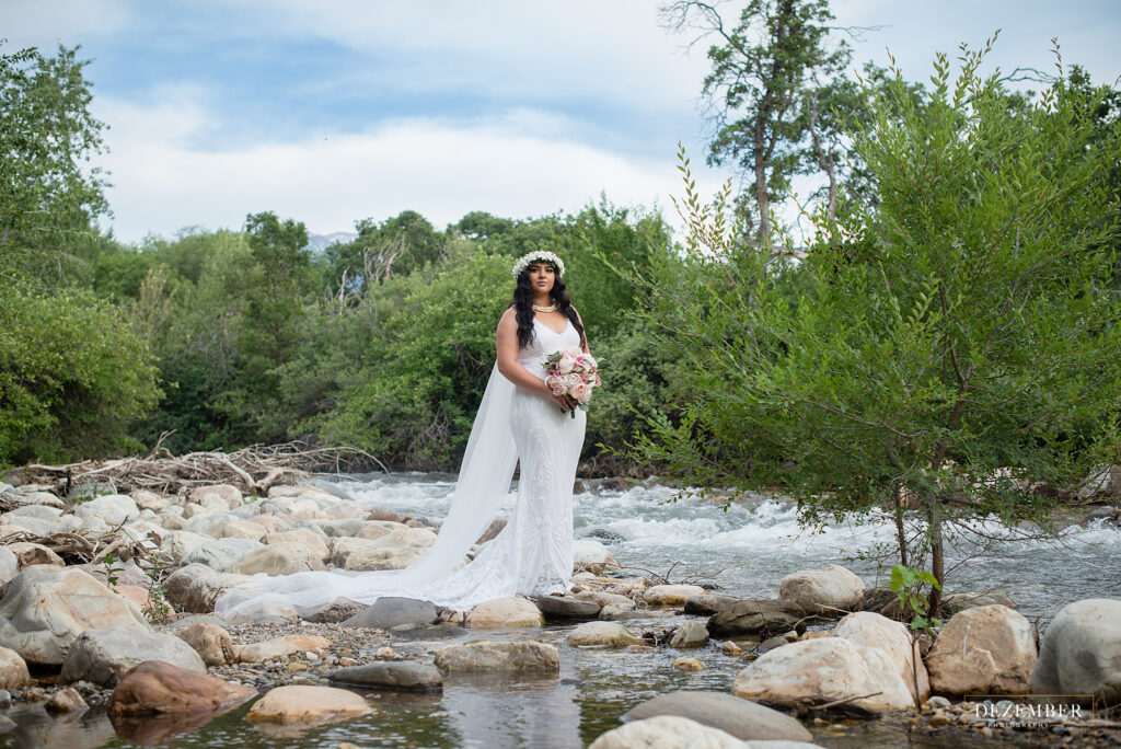 Polynesian bride stands on rocks by the river