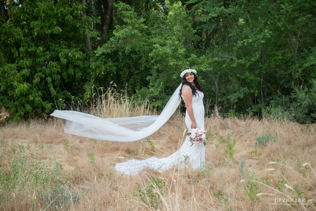 Bride with long train poses in nature