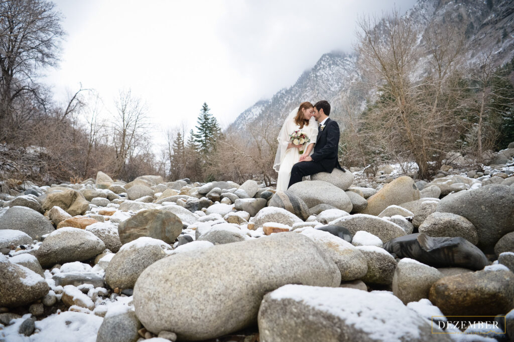 Bride and groom pose in snowy riverbed